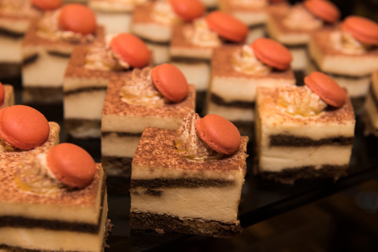 Close-up of tiramisu slices topped with macarons, perfect for a sweet treat display.